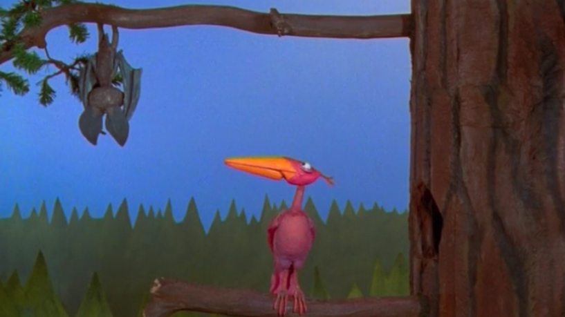 A Claymation bat hangs from a tree branch, watched by a large brightly-coloured bird on the branch below.